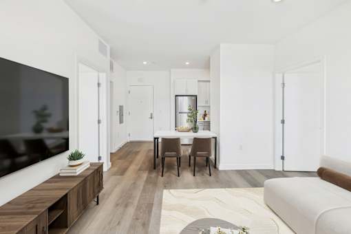 A modern living room with a white couch, a wooden table, and a flat-screen TV.