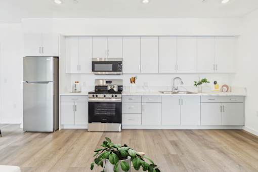 A modern kitchen with white cabinets and a wooden floor.