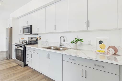 A modern kitchen with white cabinets and a marble countertop.