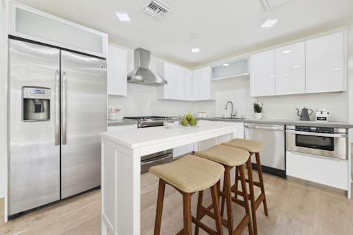 A modern kitchen with white cabinets and a stainless steel refrigerator.