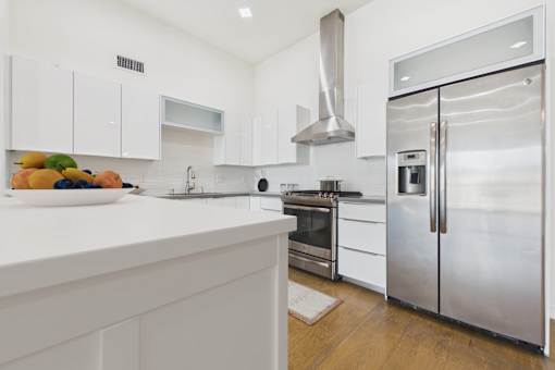 A modern kitchen with white cabinets and stainless steel appliances.