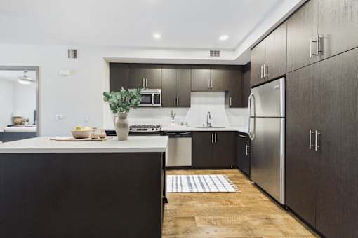 A modern kitchen with dark wood cabinets and stainless steel appliances.