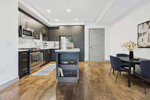 A modern kitchen with dark wood floors and a dining area with a table and chairs.