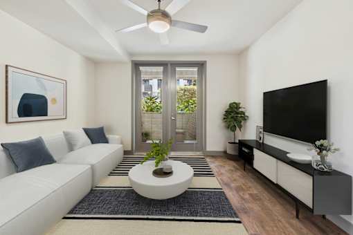 A modern living room with a white sofa, a round coffee table, and a flat-screen TV.