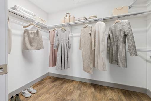 A row of clothes are hung on a rail in a white room.