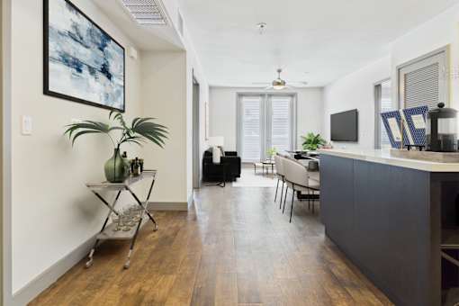 A living room with a black couch and a wooden floor.