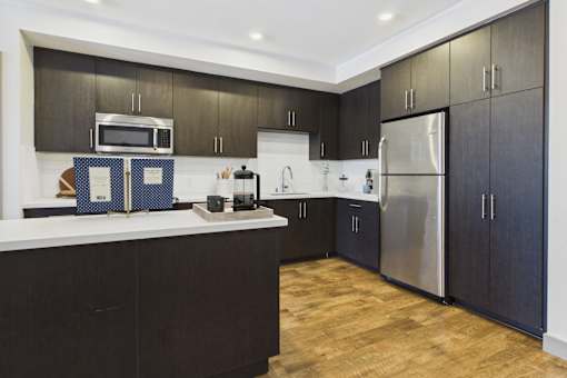 A modern kitchen with dark wood cabinets and stainless steel appliances.