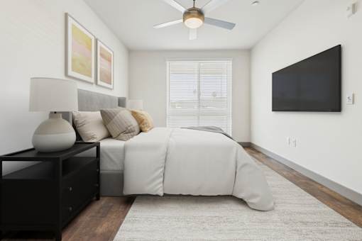 A bedroom with a bed, nightstand, and a ceiling fan.