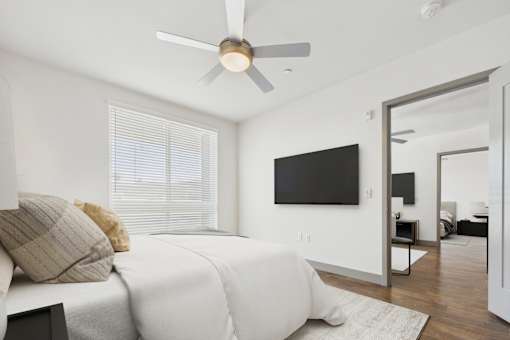 A bedroom with a bed, a ceiling fan, and a television.