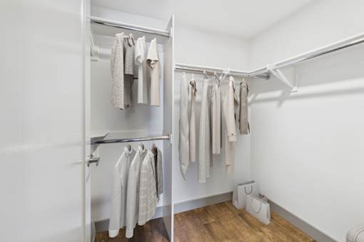 A white closet with clothes hanging on a rail.