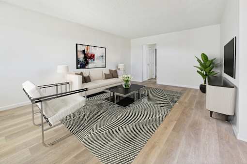 A living room with a white sofa, a coffee table, and a television.