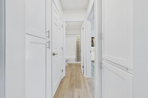 A long hallway with white doors and wood floors.