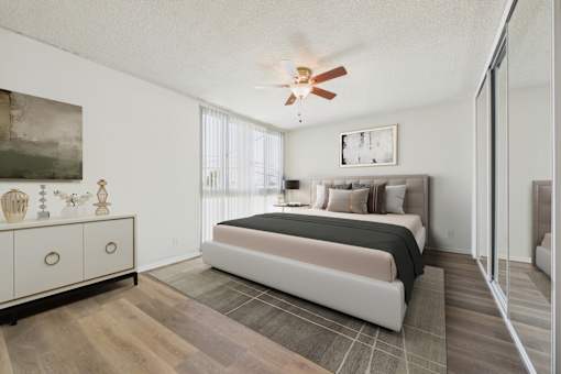 A bedroom with a bed, dresser, and a ceiling fan.