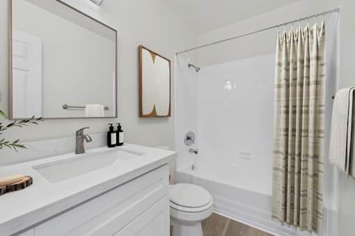 A white bathroom with a toilet, sink, and shower.