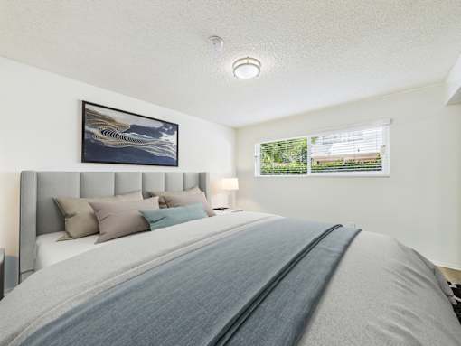 A bedroom with a large bed and a picture on the wall.