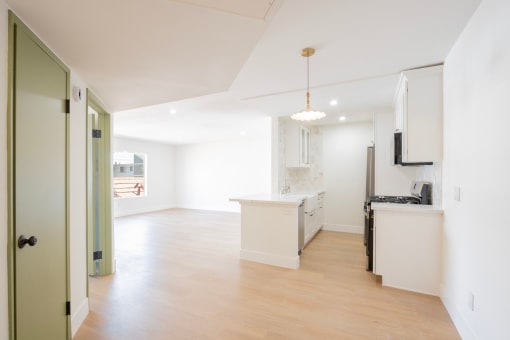 an open kitchen and living room with white walls and wood flooring