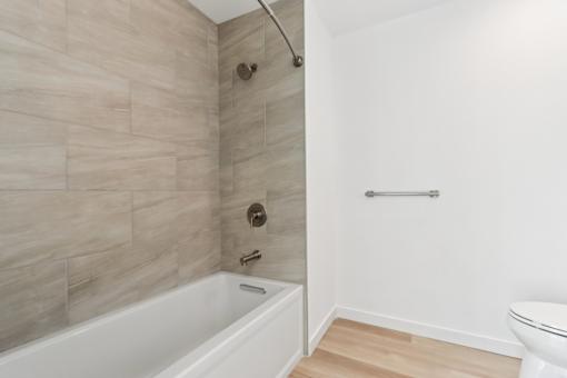 A white bathtub with a shower head and a towel bar.
