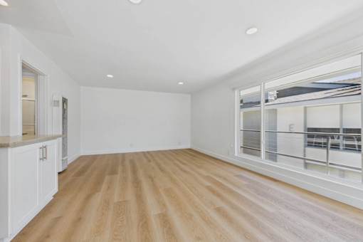 A spacious room with wooden flooring and white walls.