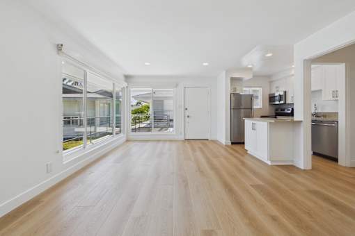 A spacious kitchen with white cabinets and a wooden floor.