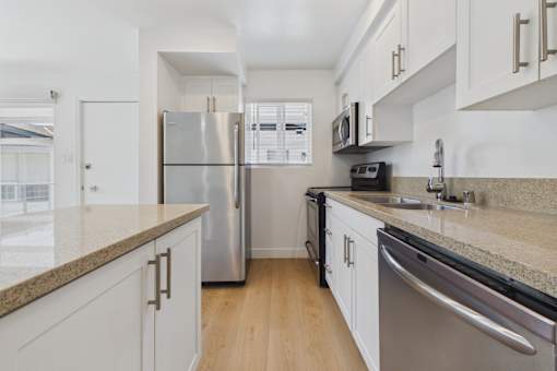 A kitchen with white cabinets and a granite countertop.