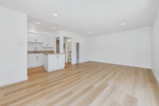 A spacious room with wooden flooring and white walls.