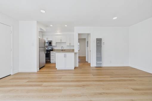 A kitchen with white cabinets and a wooden floor.