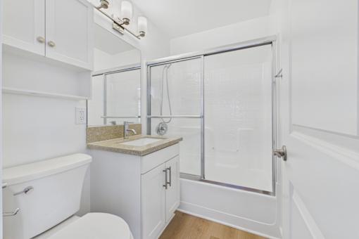 A white bathroom with a toilet, sink, and shower.