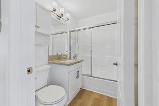 A white bathroom with a toilet, sink, and shower.