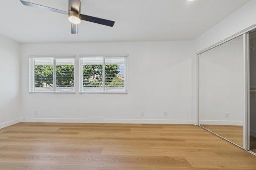 A room with a ceiling fan and a sliding glass door.