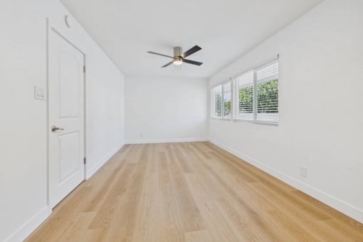 A room with a ceiling fan and wooden flooring.