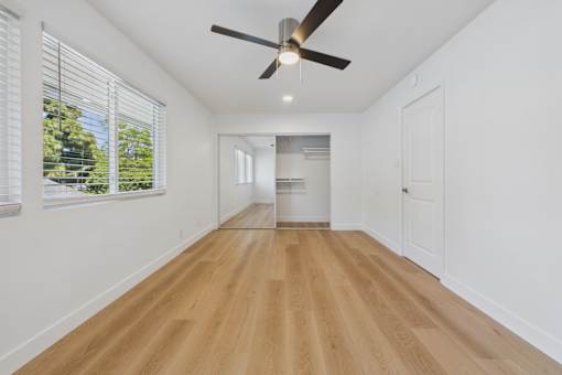 A room with a ceiling fan and wooden flooring.