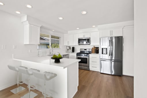 a white kitchen with a large island and stainless steel appliances