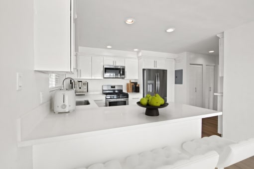 a white kitchen with a bowl of fruit on the counter