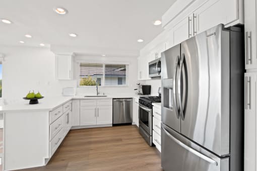 a white kitchen with stainless steel appliances and white cabinets
