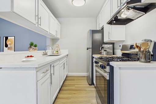 A kitchen with white cabinets and a black refrigerator.