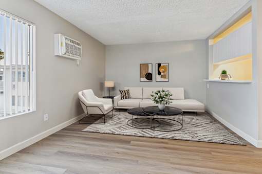A living room with a white couch, a black coffee table, and a white chair.