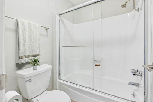 A white toilet sits next to a white bathtub in a bathroom.