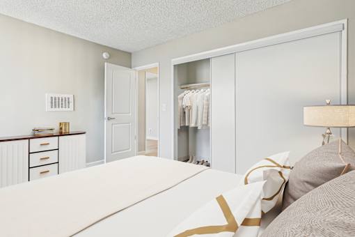 A bedroom with a bed, dresser, and closet.