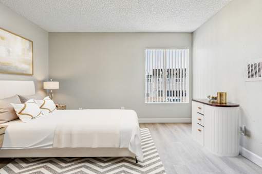 A bedroom with a large bed and a nightstand with a lamp.