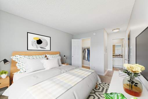 A bedroom with a bed, a nightstand, a lamp, a painting, a vase with a yellow rose, and a mirror.