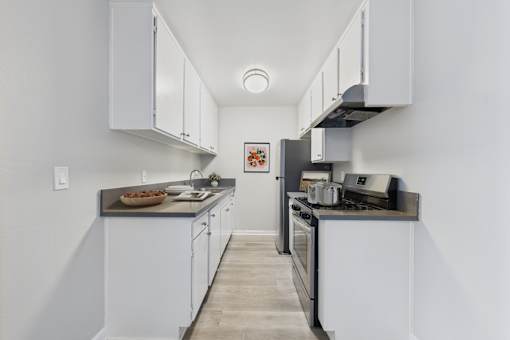 A kitchen with white cabinets and a black stove top oven.