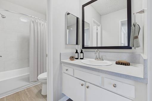 A white bathroom with a sink, mirror, and shower.