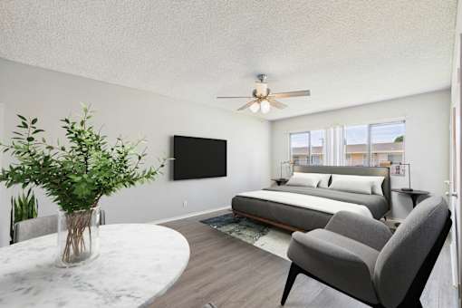 A modern bedroom with a large bed, a flat screen TV, and a ceiling fan.