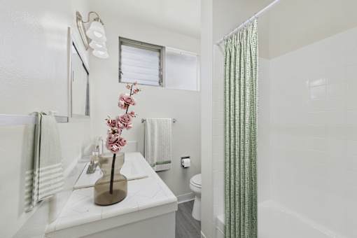 A white bathroom with a green shower curtain.