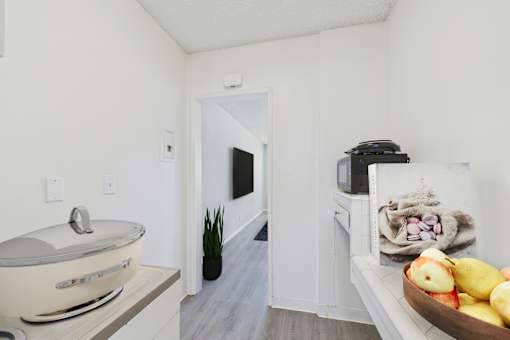 A bathroom with a tub, a plant, and a bowl of fruit.