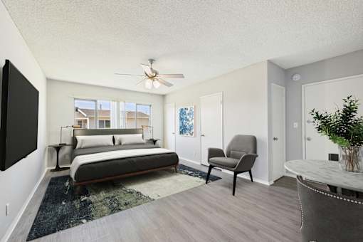 A bedroom with a bed, chair, and a ceiling fan.