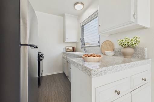 A kitchen with a refrigerator, countertop, and cabinets.