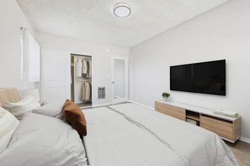 A bedroom with a large bed and a flat screen TV mounted on the wall.