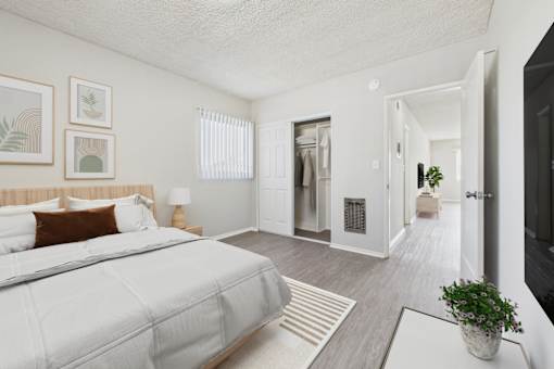 A bedroom with a large bed and a plant on the table.