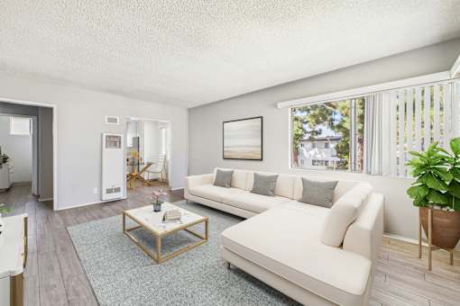 A living room with a white couch and a glass coffee table.